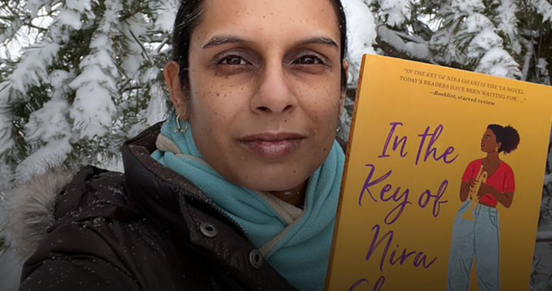 Natasha Deen, author, holding up her book In the Key of Nira Ghani